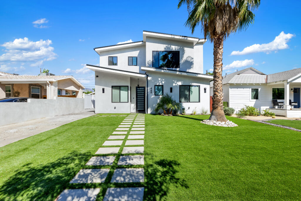 Custom modern new construction home with mid-century-inspired rooflines, dove gray stucco exterior, and black window framing.