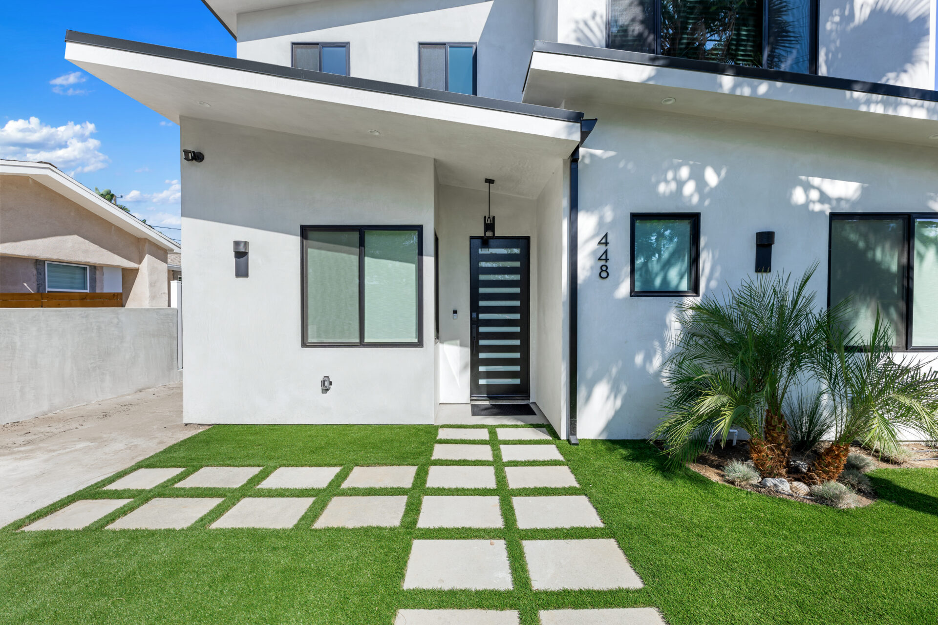Modern home exterior with standing seam roof, geometric walkway, and palm landscaping for California curb appeal.