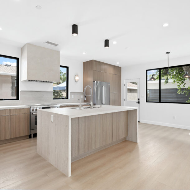 Contemporary open-concept kitchen with limestone plaster custom hood, oak cabinetry, and minimalist pendant lighting.