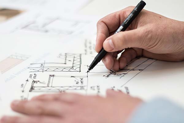 Close-up of a designer hand-drawing architectural plans with a fine-tip marker on a custom home blueprint