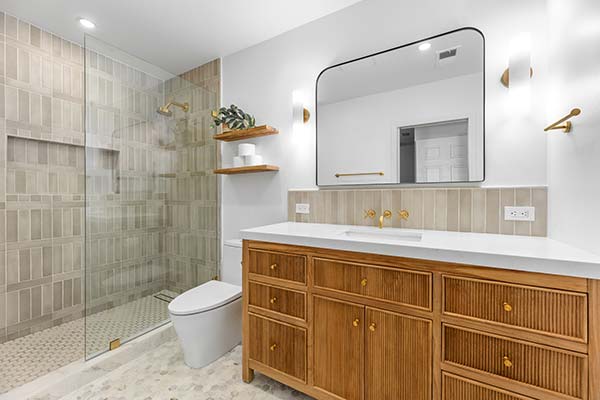 Custom bathroom remodel with a marble shower, wood vanity, dual sinks, and high-end finishes